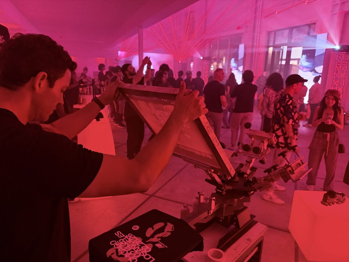 Crew member working a press under pink lighting at a nighttime tent party