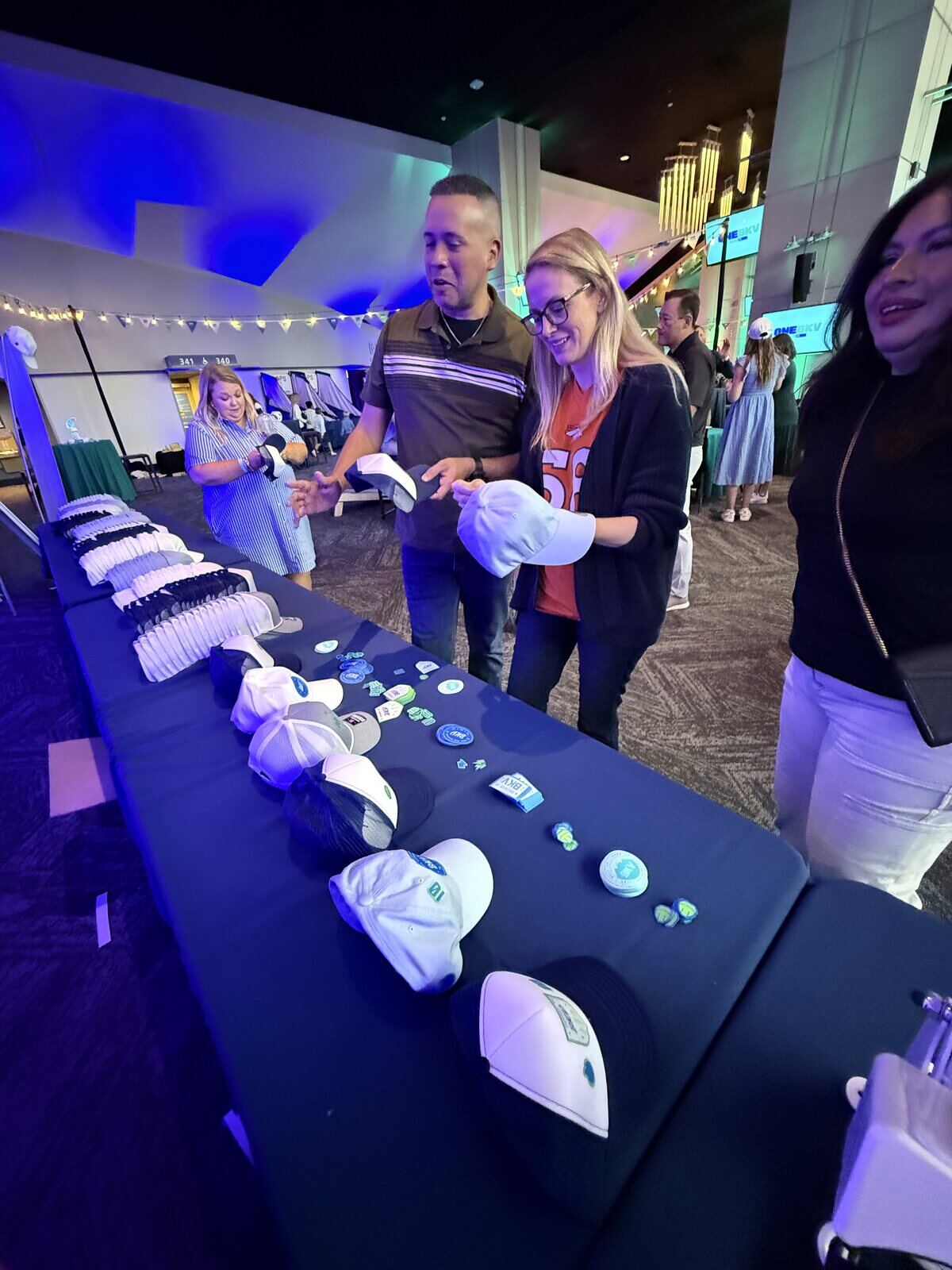 Guests choosing custom patches for white and navy bucket hats at an evening Custom Patch Bar table