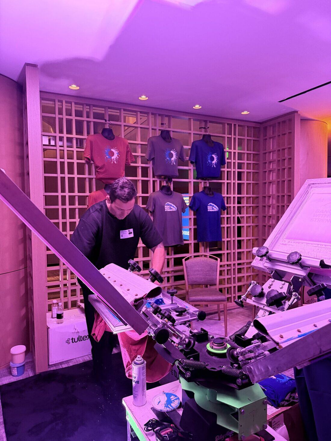 Live customization station set in front of a display wall of finished shirts at an upscale venue